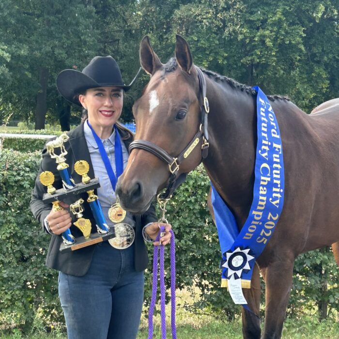Anna Schmoekel mit einem Pferd, das mit Auszeichnungen und einem blauen Siegerband für den Futurity Champion 2025 dekoriert ist.
